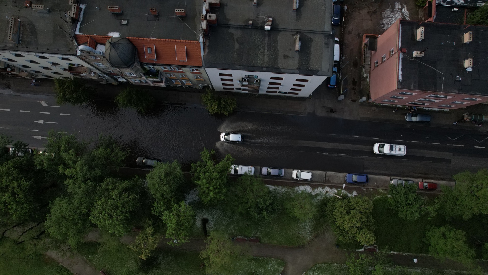 Aerial view of cars driving through a flooded urban street after a storm