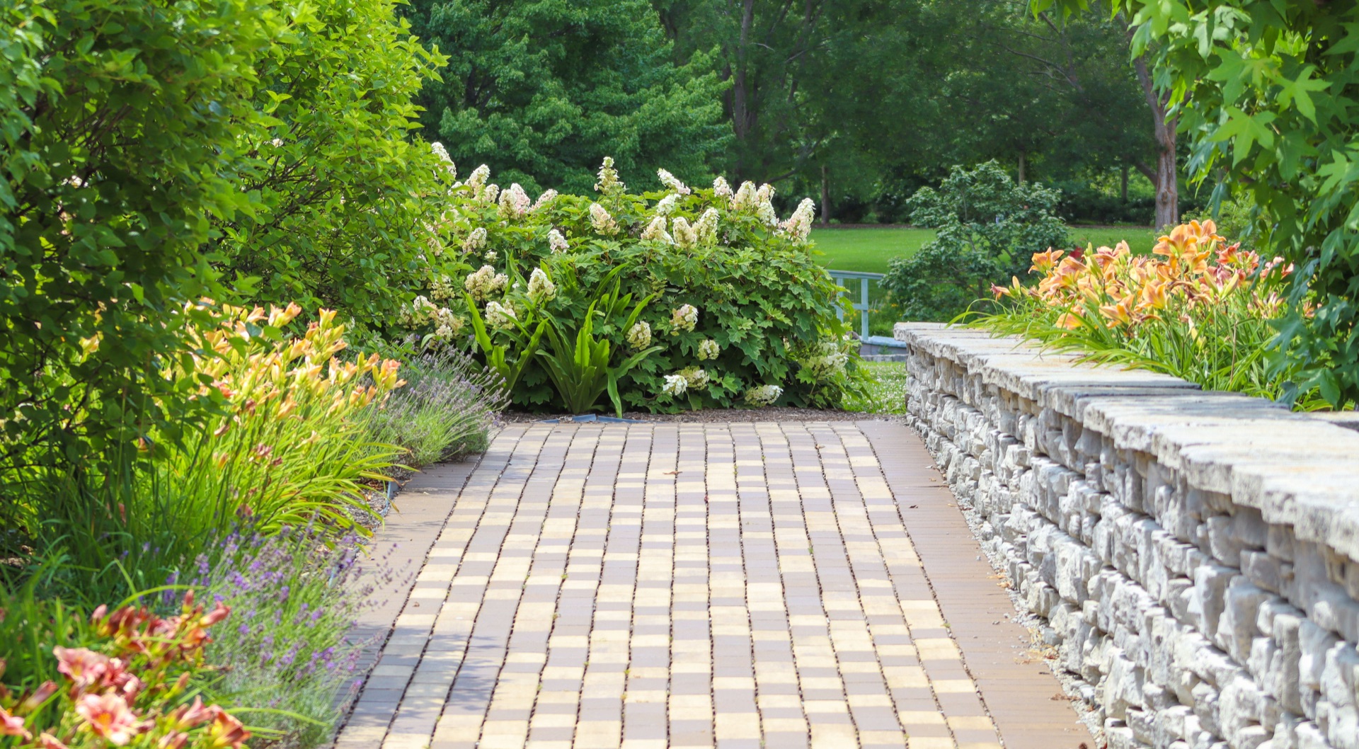 Aesthetic permeable paver walkway lined with lush greenery and flowers